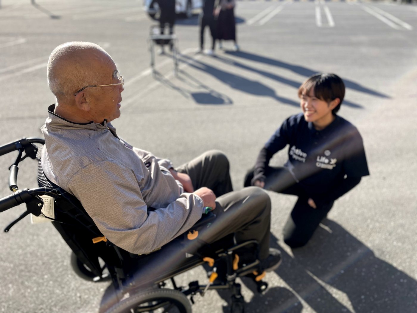 車いすのご利用者と目線を合わせて話すナガヨシのスタッフ