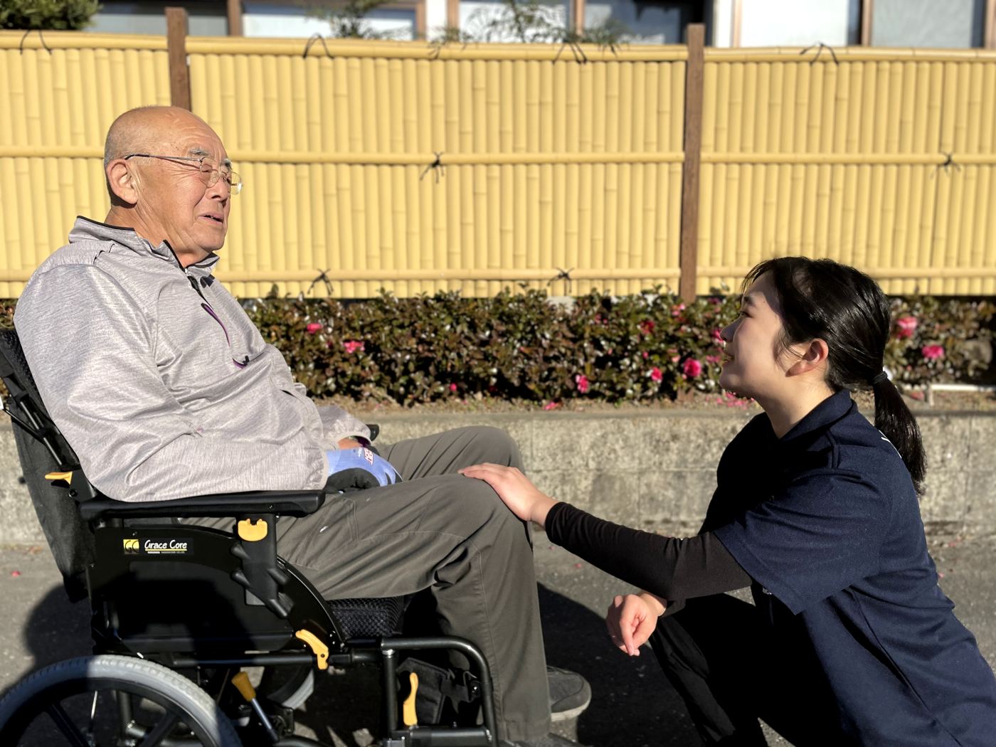 車いすの方の前にしゃがみ、目線を合わせて話す相談員