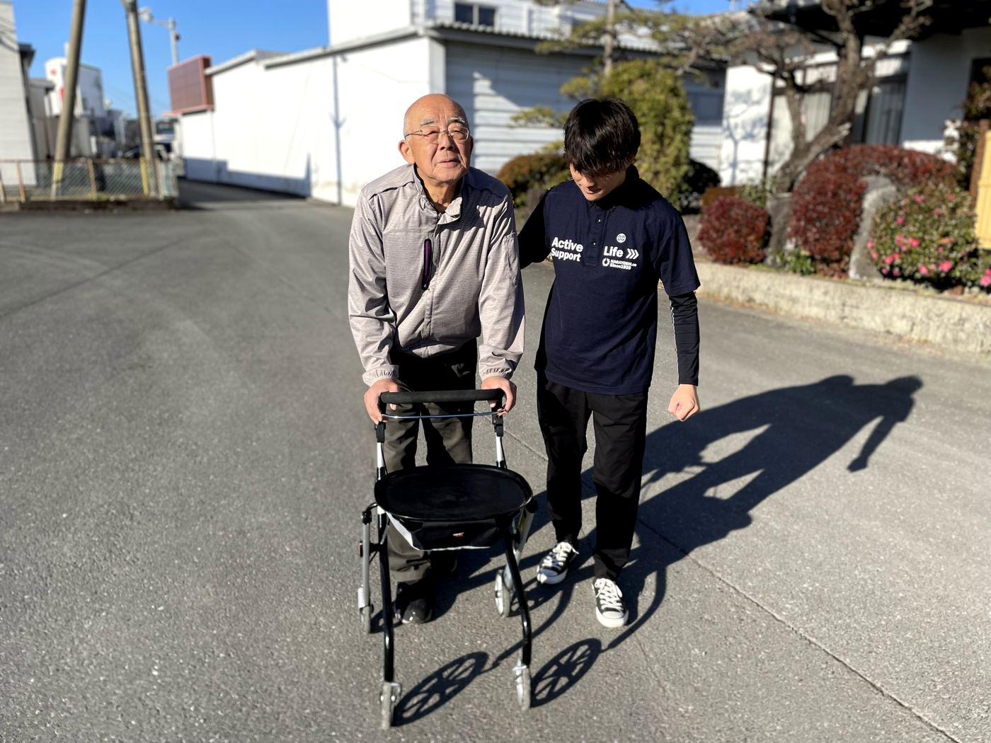 歩行器を使う方の横について一緒に歩く相談員